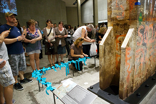 Visitors tie blue ribbons on a railing surrounding the Last Column during a ceremony on May 30, 2015.