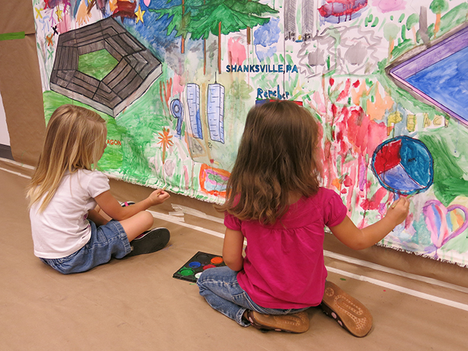 Two young girls pain a mural commemorating victims of 9/11 in the Museum’s Education Center. The mural includes drawings of the Twin Towers and Pentagon, as well as hearts and a peace sign.