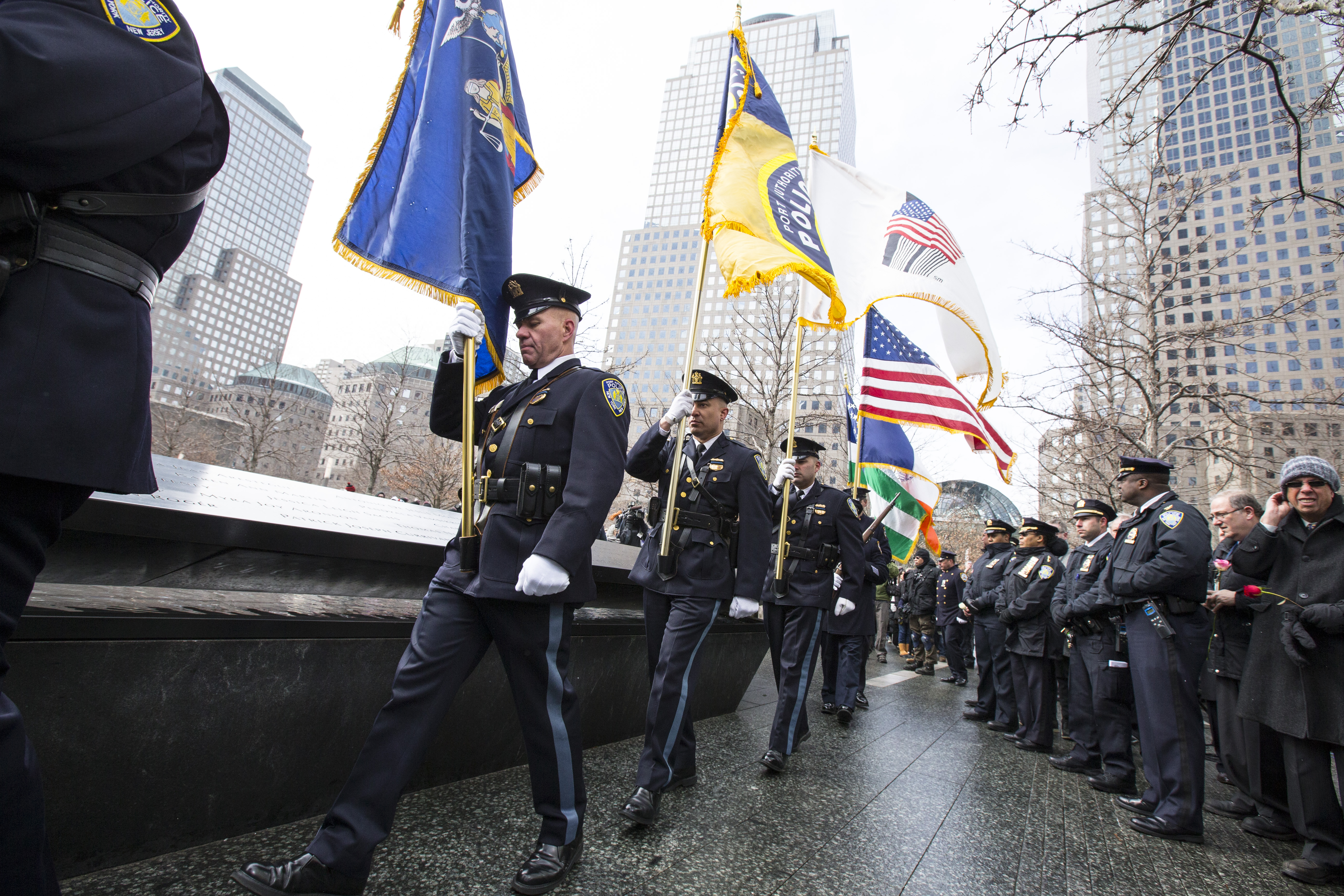 Police officers carry flags as they walk past a reflecting pool at the 9/11 Memorial during the 22nd anniversary of the 1993 attack.