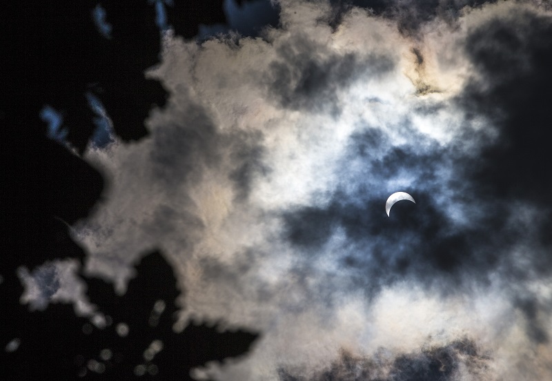 A view from the Memorial plaza shows clouds passing by the moon during the Great American Eclipse.