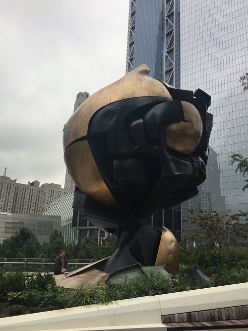 The Koenig Sphere stands in Liberty Park on a cloudy day. The park overlooks the north and south pools of the 9/11 Memorial.