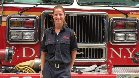 Josephine Smith stands, smiling and in uniform, in front of FDNY fire engine 39.