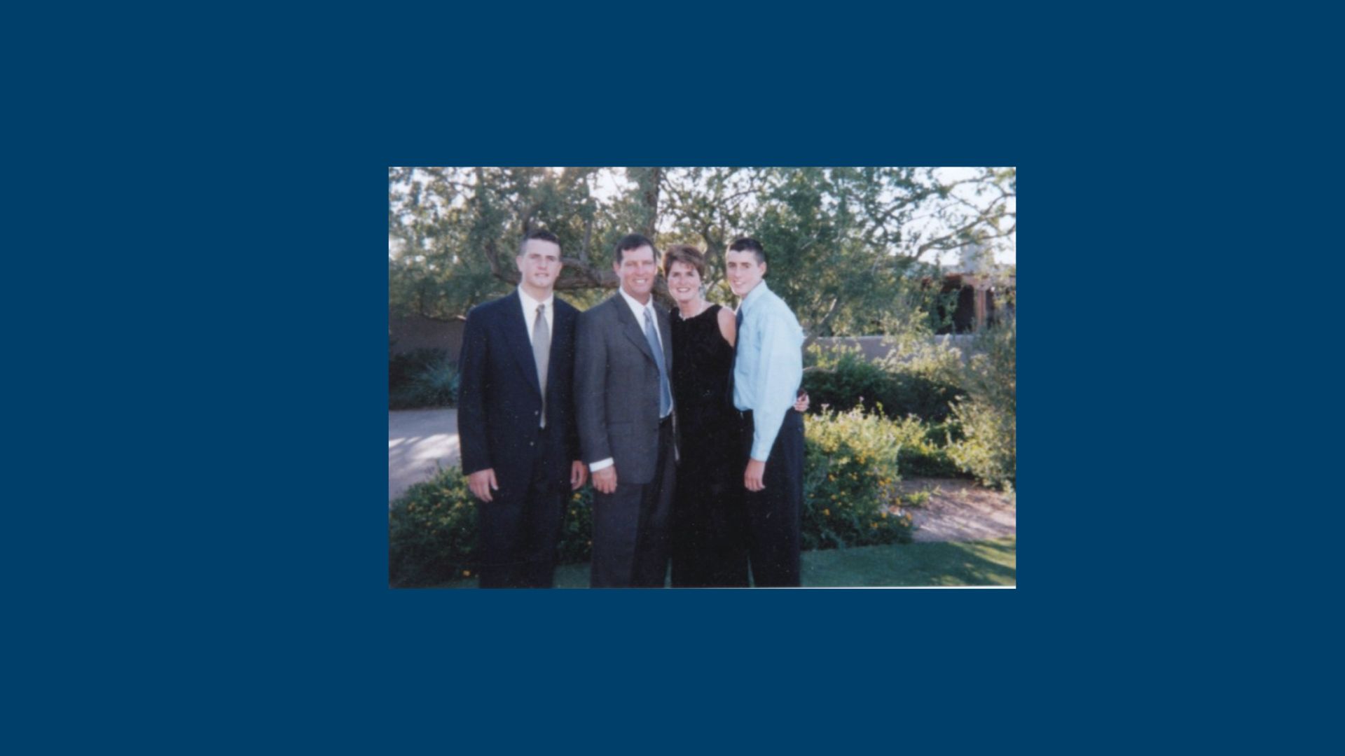 A family of four stands together outside