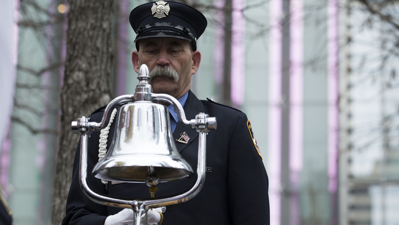 A mustachioed firefighter in a formal FDNY outfit rings a silver bell, marking the time the World Trade Center was bombed on February 26, 1993.