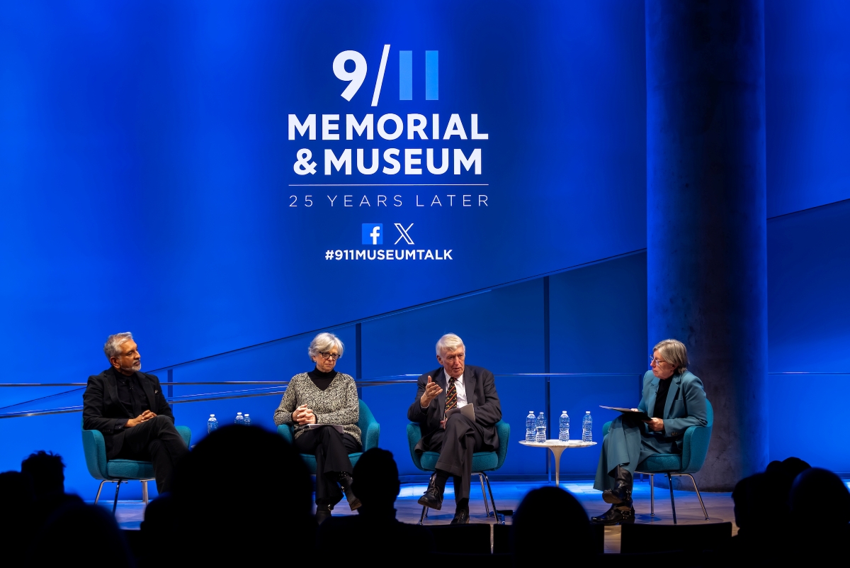 a panel of four people sit on stage in front of a blue 9/11 Memorial & Museum logo