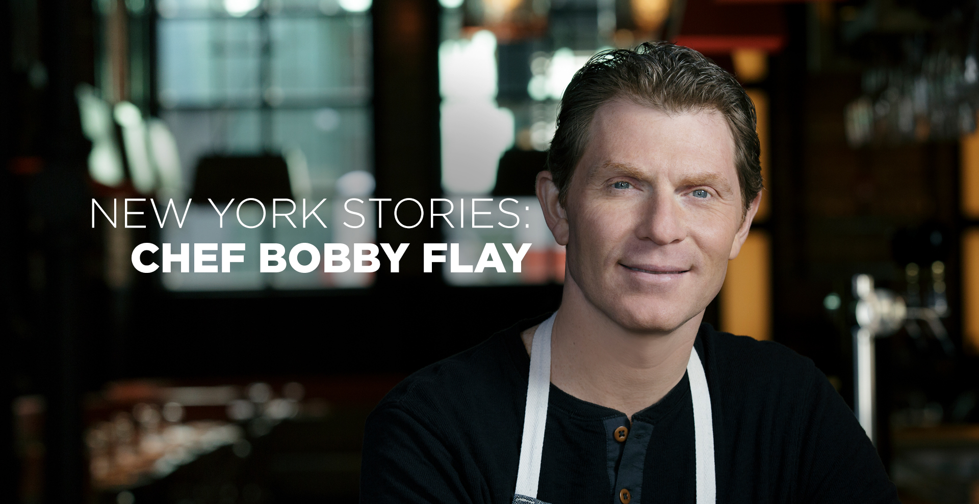 Bobby Flay smiles wearing a black tshirt and white apron. Date: May 14 at 6 pm