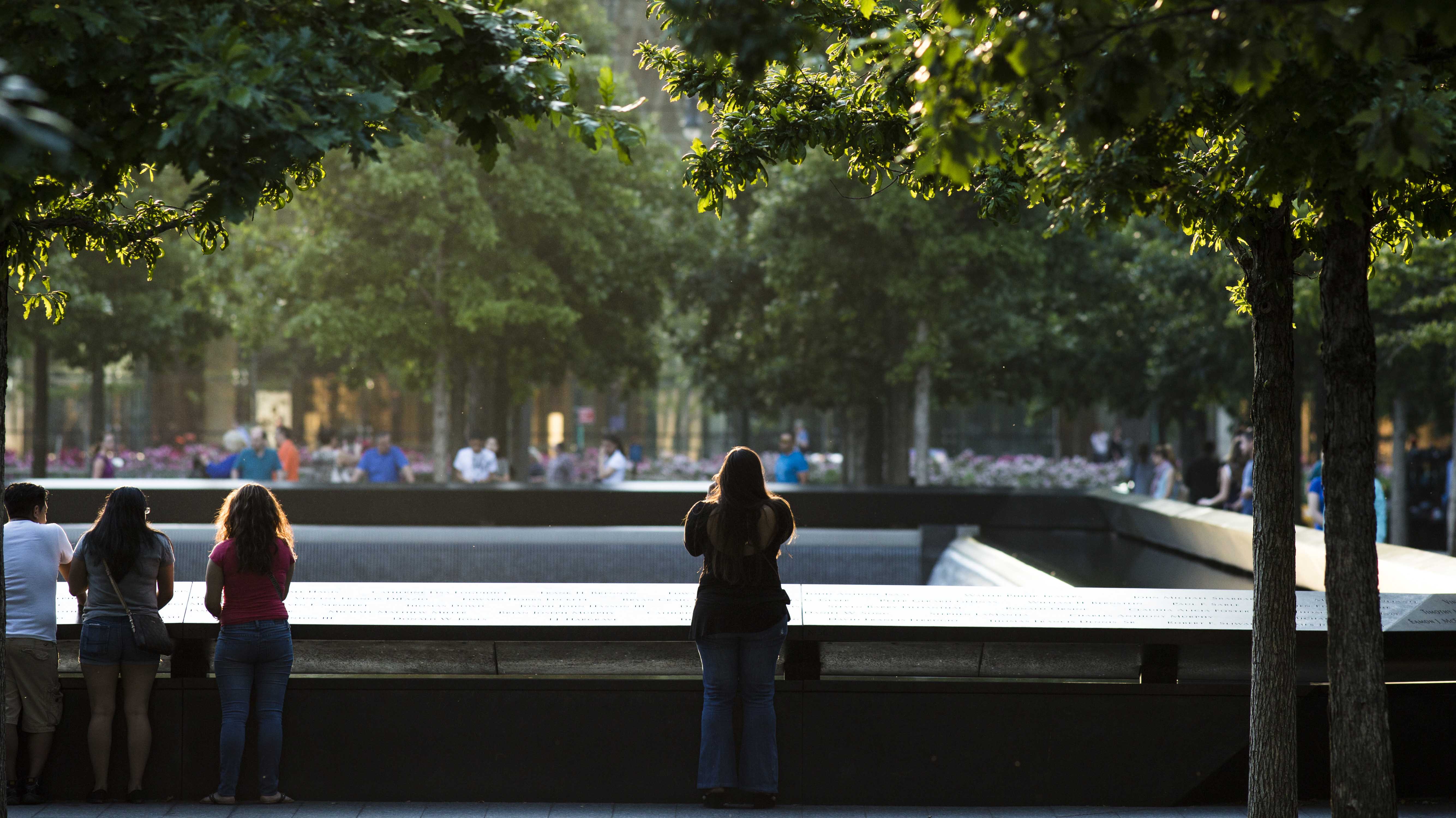 A woman is seen standing at the Memorial parapets at dusk.  She is standing alone with her back to the camera as she takes a photo.  