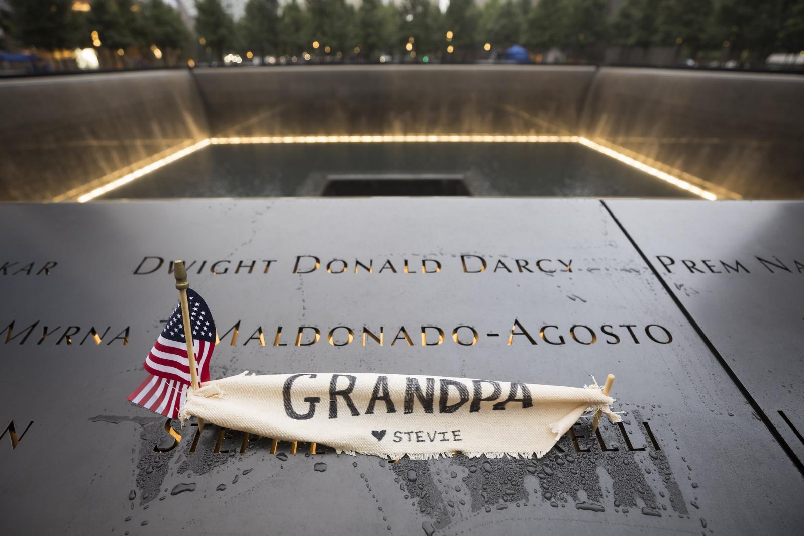 Image of the Memorial parapet at dusk with an American flag laid on a name and a small banner that says Grandpa.