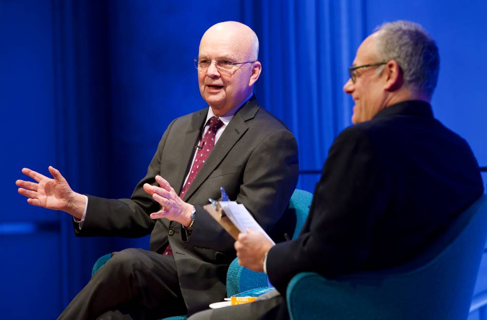 Former CIA director and retired U.S. Air Force Gen. Michael Hayden gestures with both hands onstage as part of the public program, General Michael Hayden on the War on Terror. He is seated next to Clifford Chanin, the executive vice president and deputy director for museum programs, who is smiling as he looks out at the audience.