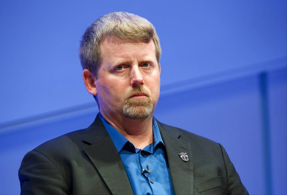 Former special forces commander retired Maj. Mark Nutsch speaks onstage as he takes part in the public program, The Horse Soldiers. The wall behind him is illuminate a light blue.