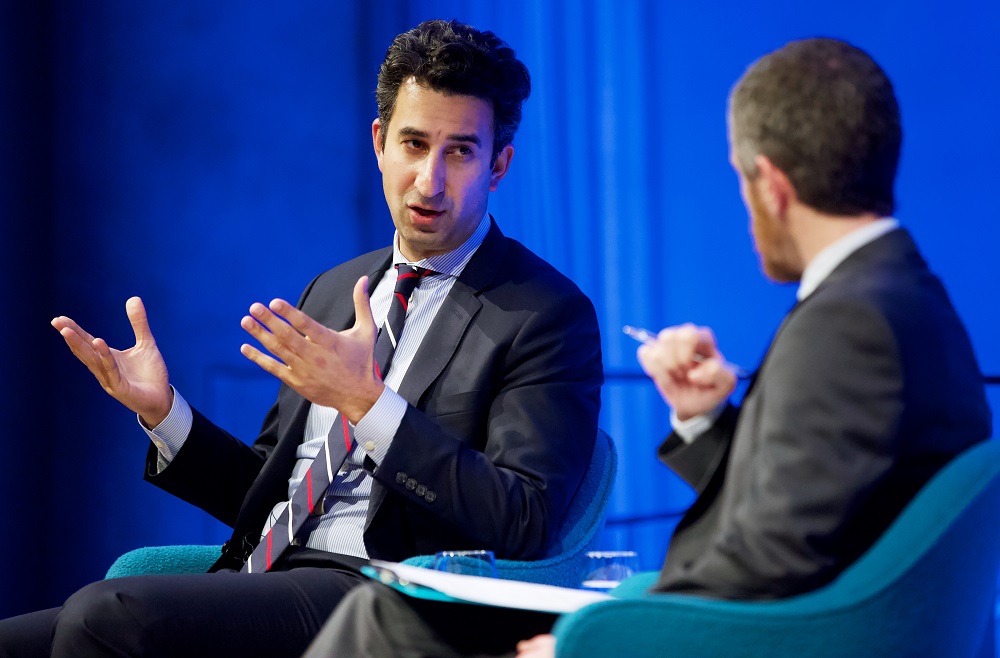 The program participant gestures with his hands and addresses the moderator.