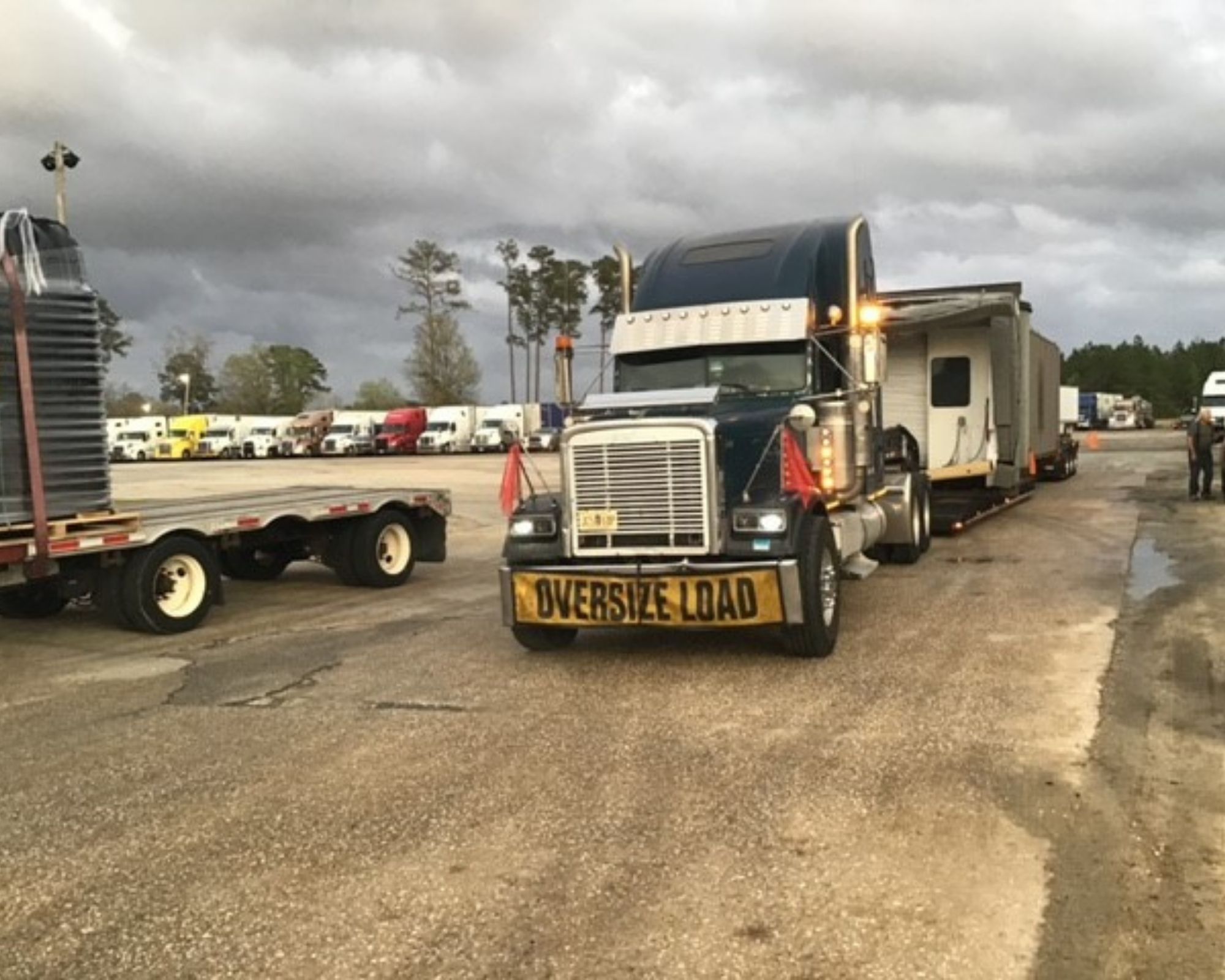 A large truck with a sign that says "Oversize Load" carrying the airport gateway