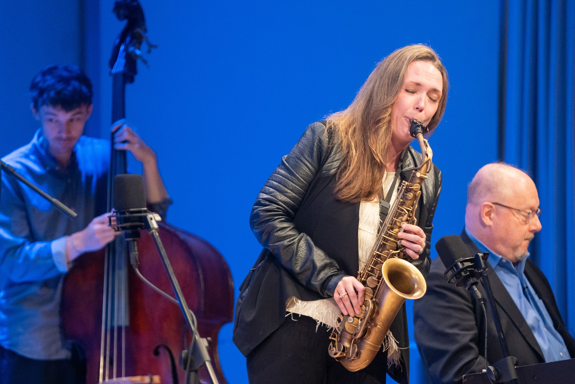 Trio of jazz players featuring saxophonist in front, bass player and keyboardist on the sides