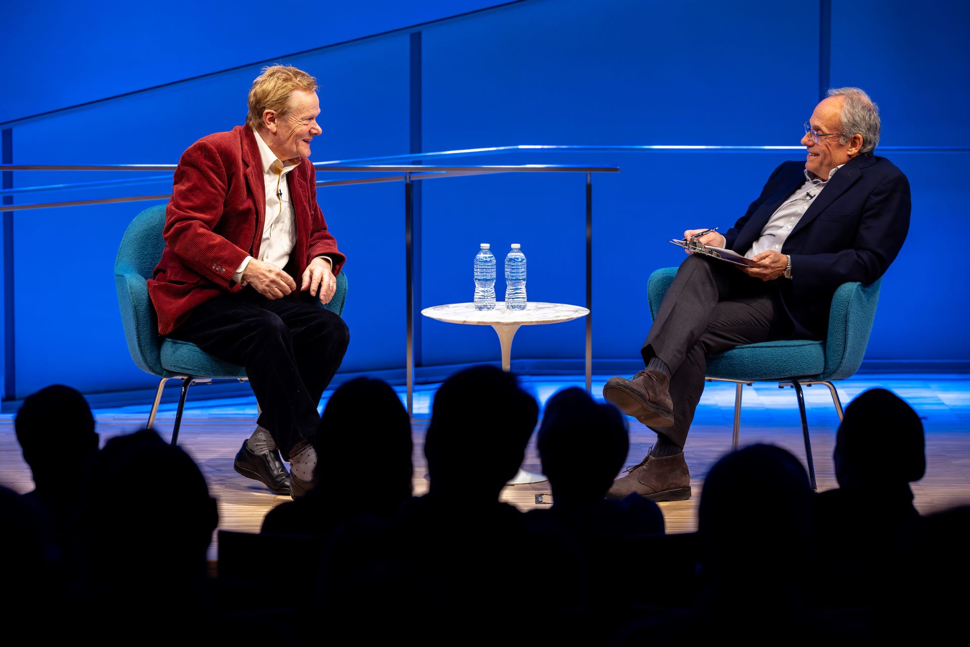 Philippe Petit and Clifford Channing sit on the stage with a table between them