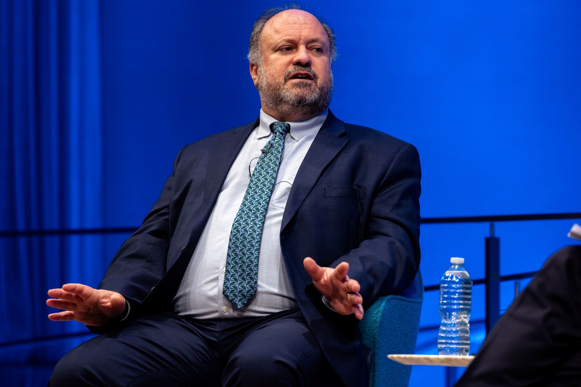 Bernard Haykel speaks on stage against a blue background.