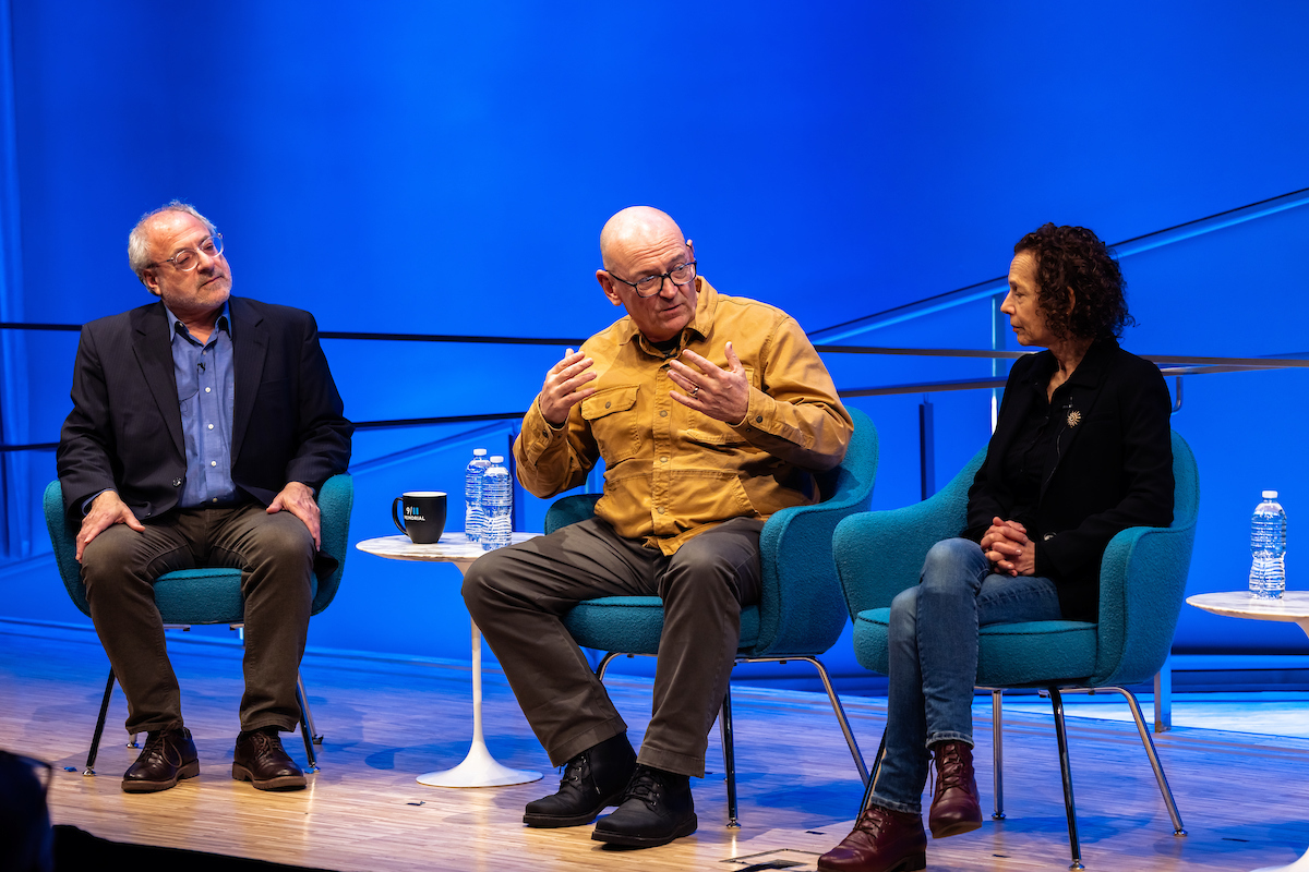 three panelists engage in conversation on stage