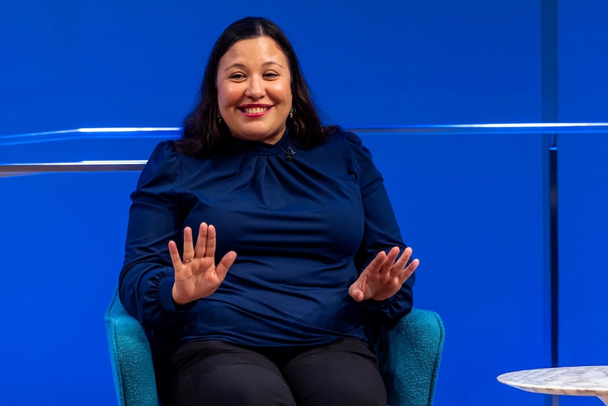 a woman in dark blue talks and gestures and smiles
