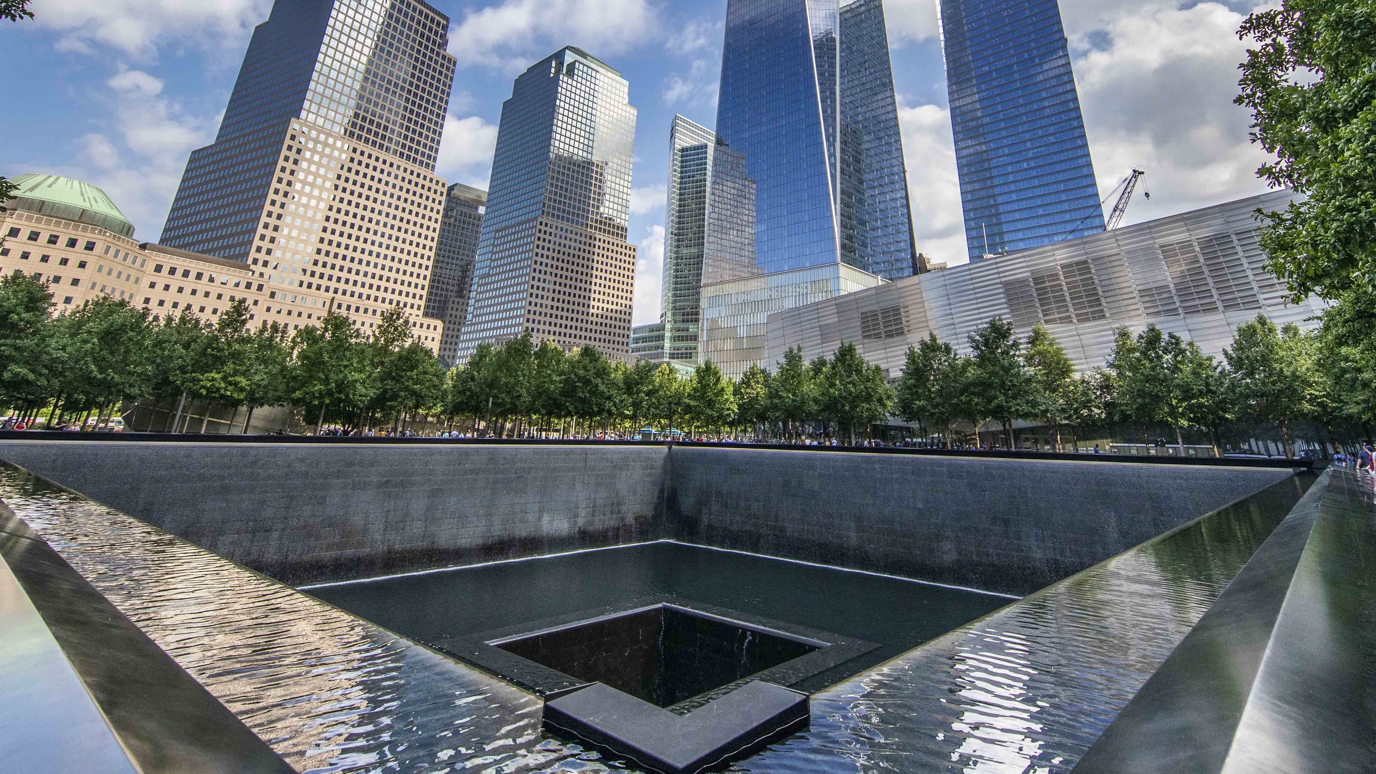 This panoramic shot is taken from the southeast corner of the north pool of the Memorial, looking northward and upward toward the soaring One World Trade.