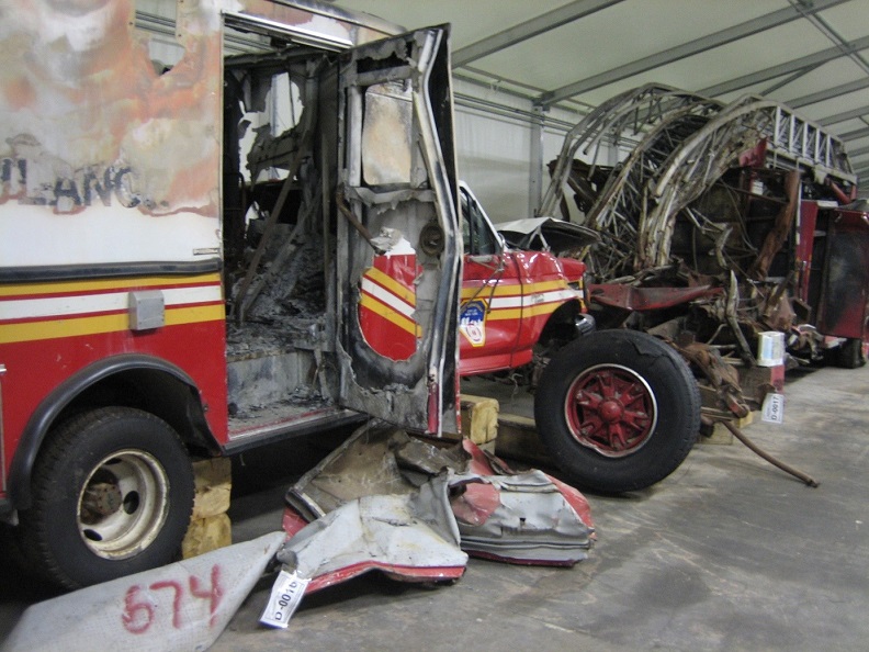 Smashed and dusty FDNY Ambulance and FDNY Ladder 3 parked at Hangar 17. 