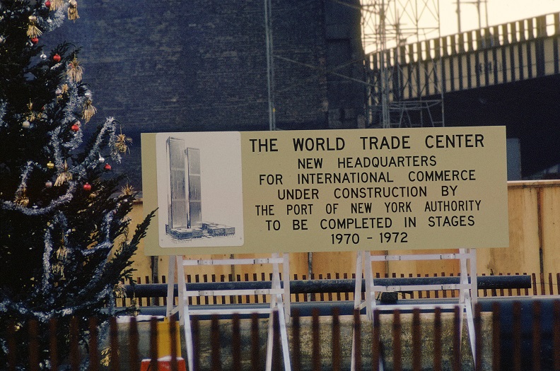 Sign in front of construction site with image of the twin towers and the text: "The World Trade Center, New Headquarters for international commerce under construction by the Port of New York Authority to be completed in stages 1970 to 1972. 
