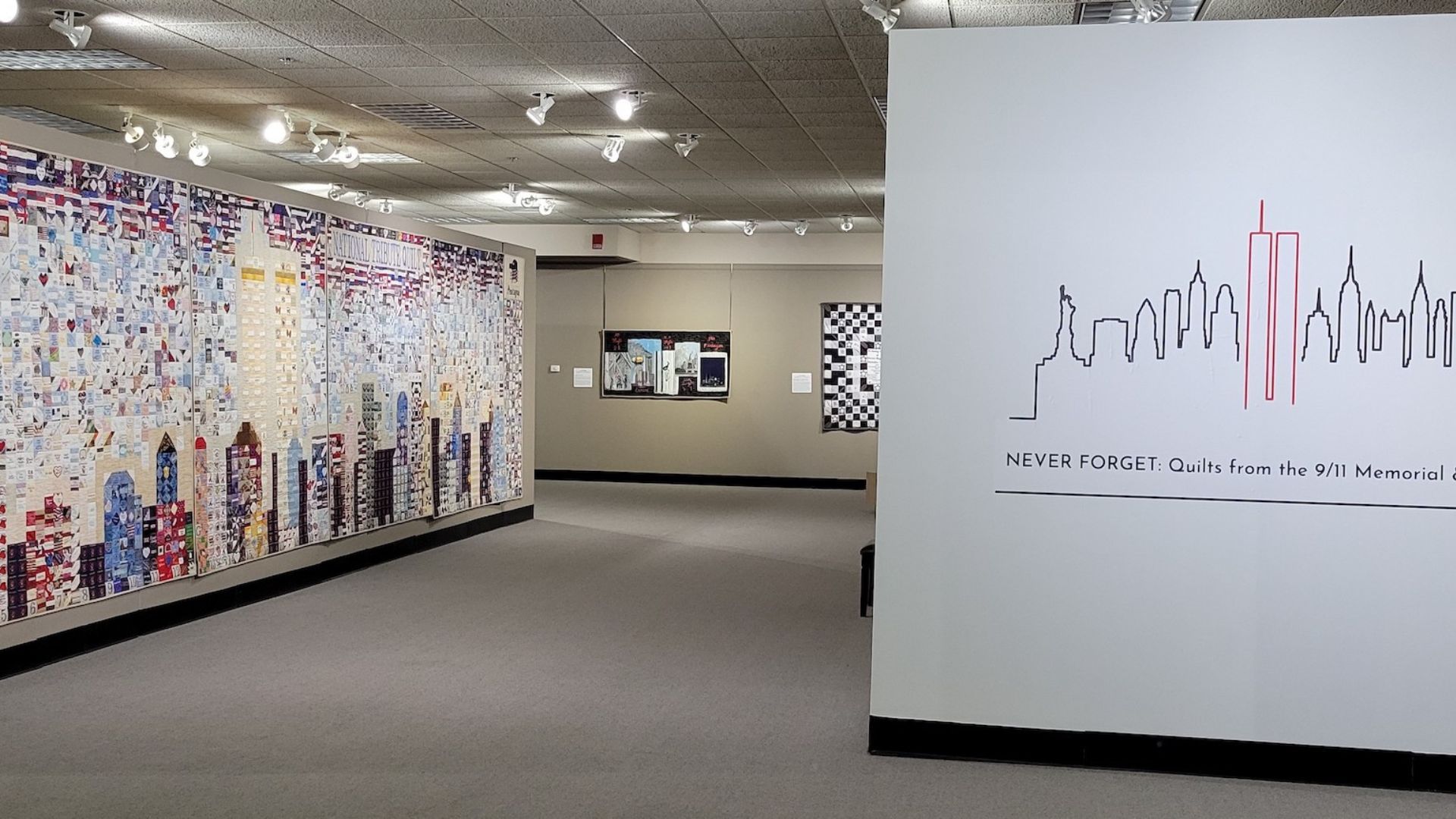 A beige-carpeted gallery space, brightly lit, displays quilts from the Museum's collection 