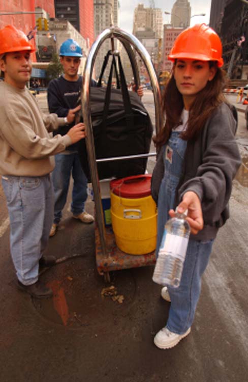 Volunteers in red hard hats hand out water bottles at Ground Zero