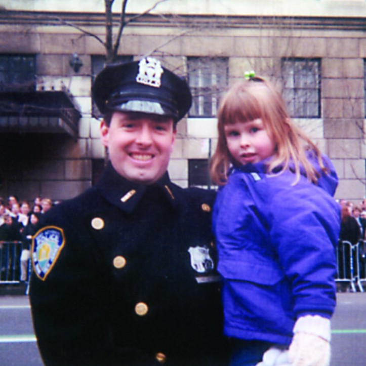 a man in police uniform holds a young girl in a purple coat
