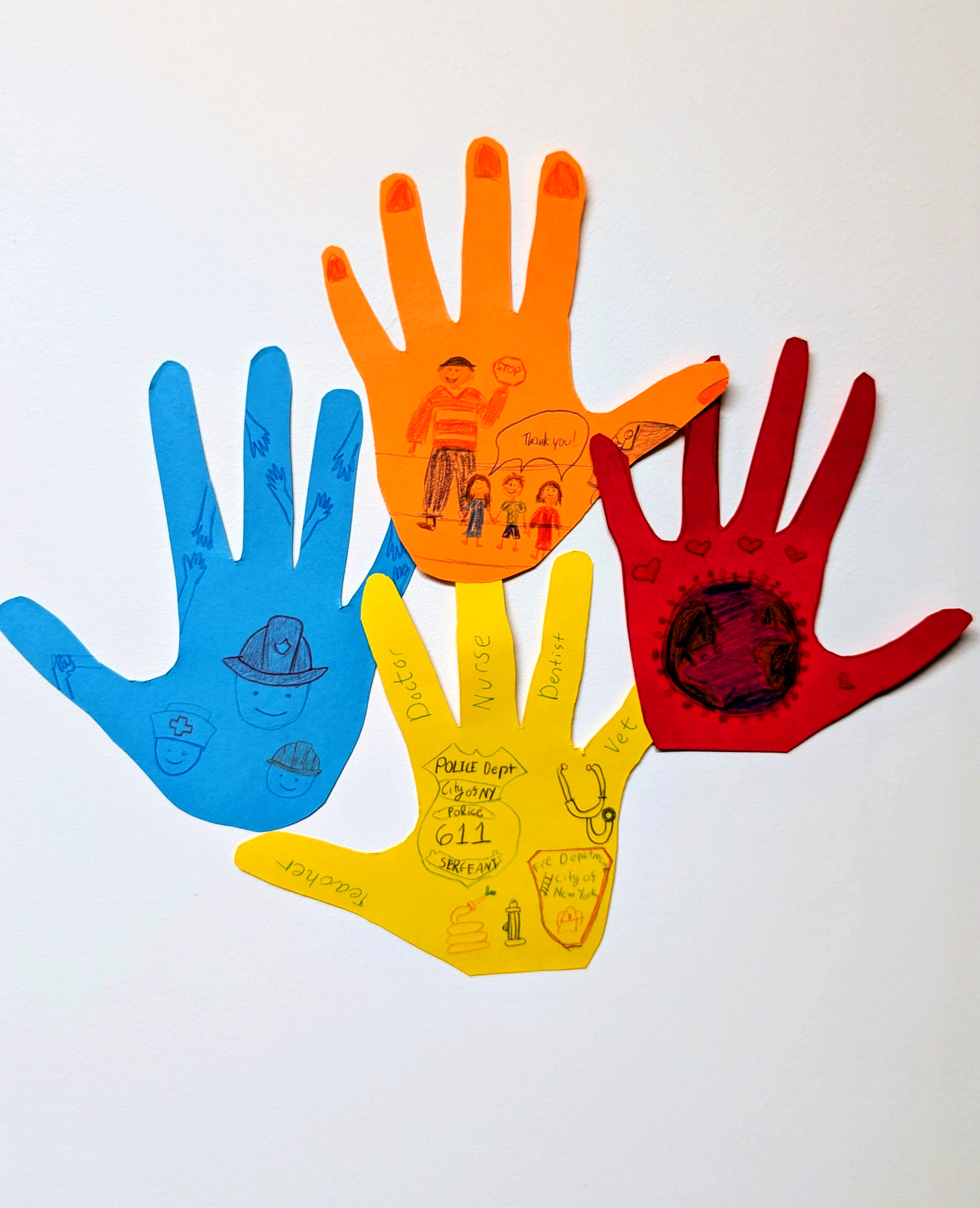 Handprints cut out of blue, orange, yellow, and red construction paper. The handprints are decorated with children's drawings.