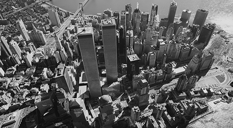 Aerial view of lower Manhattan with Twin Towers on a sunny day. The black and white image has a fishbowl effect.