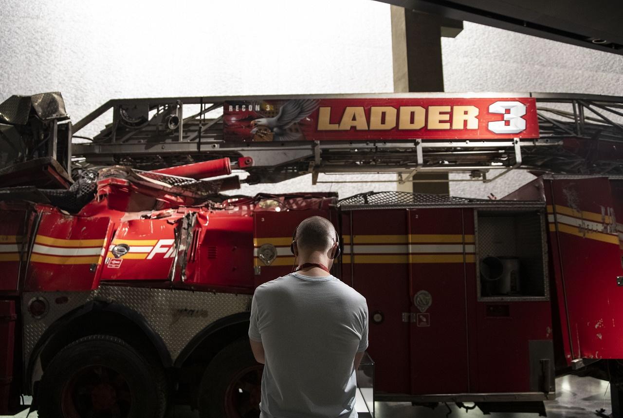A museum visitor stands with his back to the camera in front of the Ladder 3 firetruck in the museum.