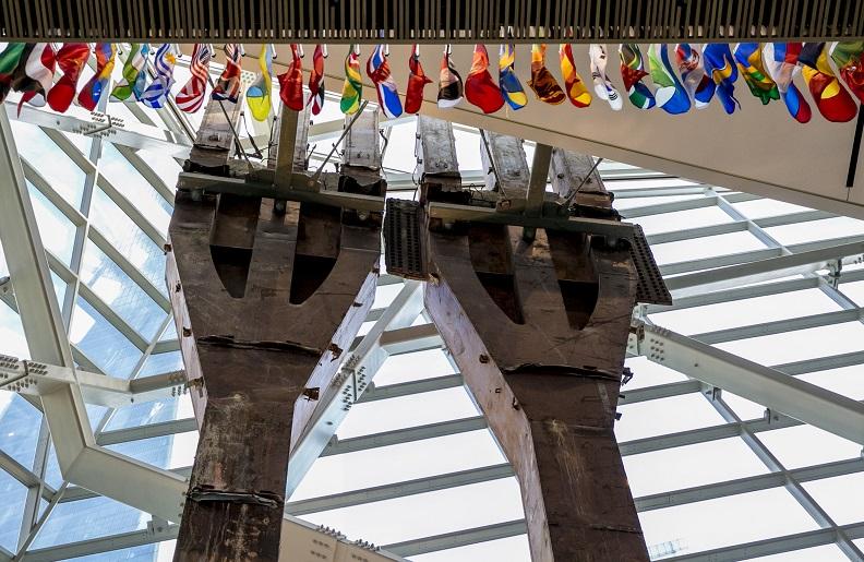 Two eighty-foot tall steel columns, known as the Tridents, tower over the interior of the museum Pavilion. One World Trade Center points skyward outside the windows.