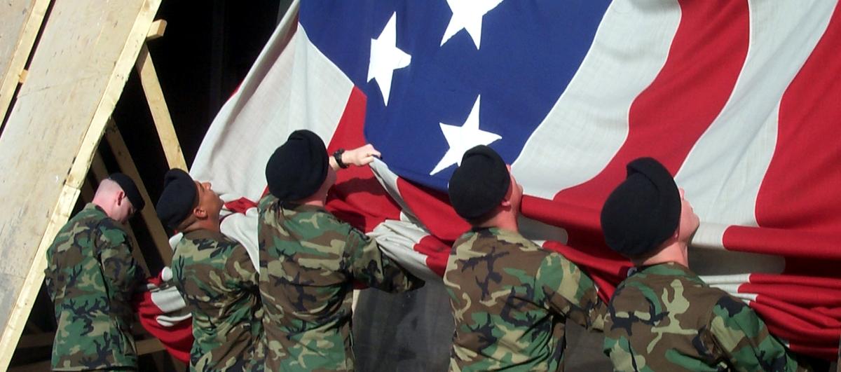 Soldiers in berets raise a giant flag at Ground Zero