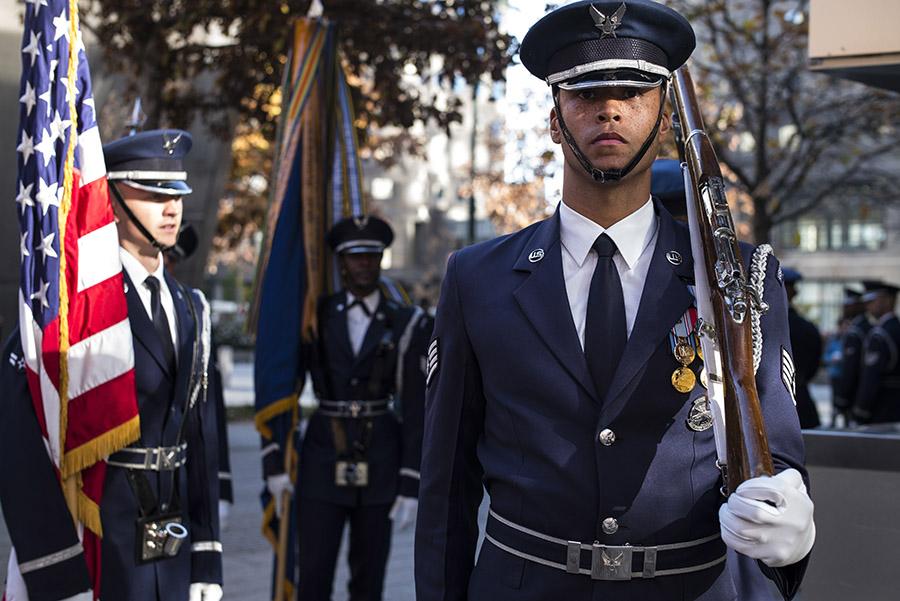 Formally dressed members of the Air Force carrying flags and rifles stand at the 9/11 Memorial.