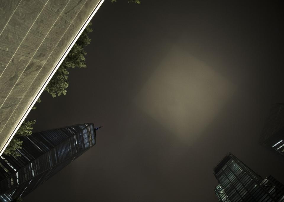 A rectangular patch of light shines into the night sky from inside the Memorial pool.