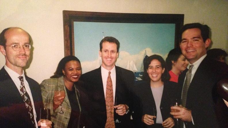 A group of young professionals stand together and smile for the camera during an office party.